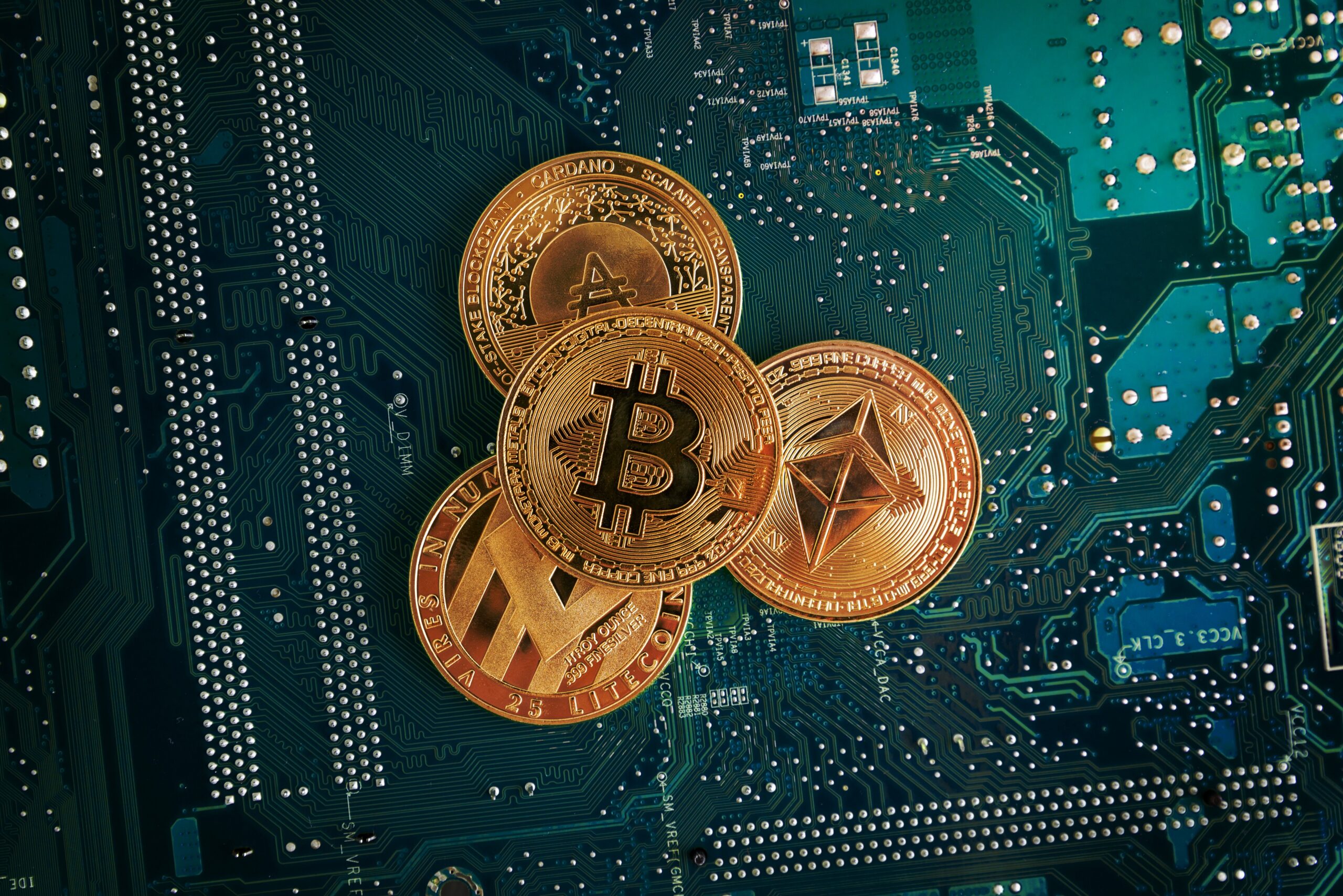 A closeup of Bitcoin, Ethereum, Litecoin and Cardano coins on the electronic circuit board.